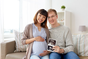 Image showing happy couple with ultrasound images at home