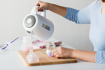 Image showing hands with kettle and bottle making baby milk