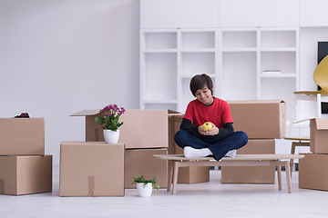 Image showing boy sitting on the table with cardboard boxes around him