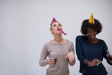 Image showing smiling women in party caps blowing to whistles