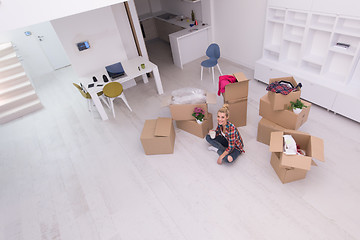 Image showing woman with many cardboard boxes sitting on floor