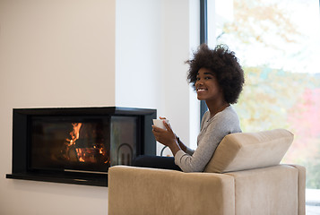 Image showing black woman drinking coffee in front of fireplace