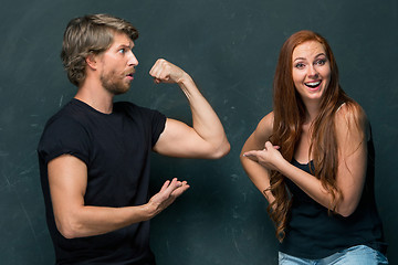 Image showing Beautiful woman impressed by the muscles of a bodybuilder, strong man showing off his muscles