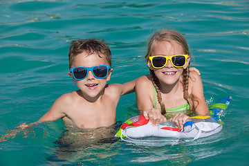 Image showing Two happy children playing on the swimming pool at the day time.