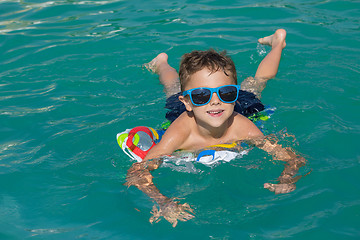 Image showing happy child playing on the swimming pool at the day time.