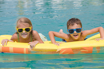 Image showing Two happy children playing on the swimming pool at the day time.