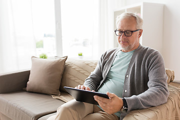 Image showing senior man with tablet pc sitting on sofa at home