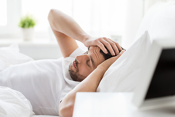 Image showing man in bed at home suffering from headache