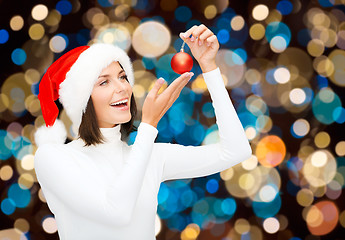 Image showing happy woman in santa hat with christmas ball