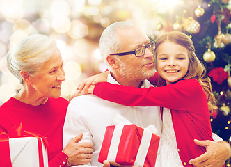 Image showing happy family with christmas gifts over lights