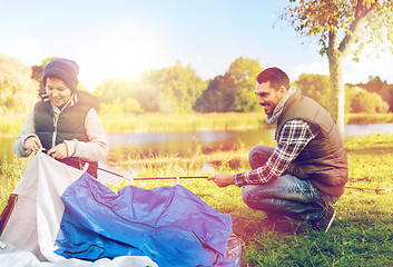 Image showing happy father and son setting up tent outdoors