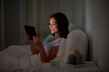 Image showing young woman with tablet pc in bed at home bedroom