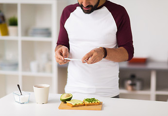 Image showing man photographing food by smartphone at home