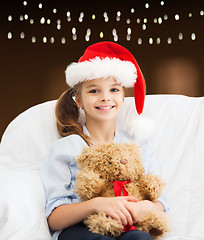 Image showing girl in santa hat with teddy bear at christmas