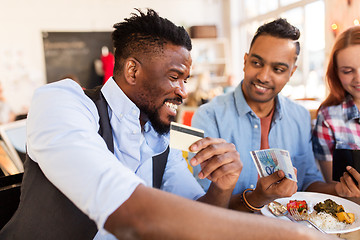 Image showing happy friends with money paying bill at restaurant