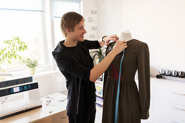 Image showing fashion designer with dummy making dress at studio