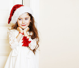 Image showing little cute girl in santas red hat waiting for Christmas gifts. 