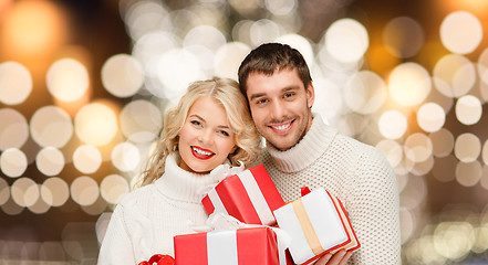 Image showing happy couple in sweaters holding christmas gifts