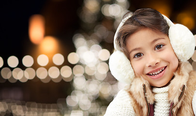 Image showing happy girl wearing earmuffs over christmas lights