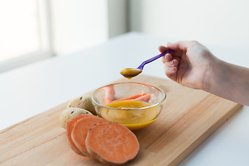 Image showing hand with vegetable puree or baby food in spoon