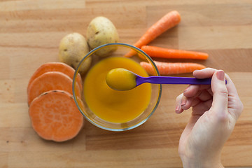 Image showing hand with vegetable puree or baby food in spoon