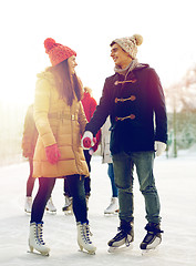 Image showing happy friends ice skating on rink outdoors