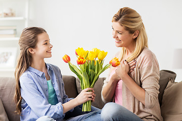 Image showing happy girl giving flowers to mother at home