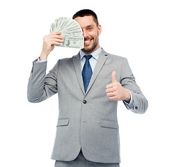 Image showing smiling businessman with money showing thumbs up