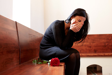 Image showing crying woman with red rose at funeral in church