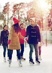 Image showing happy friends ice skating on rink outdoors