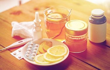 Image showing drugs, thermometer, honey and cup of tea on wood