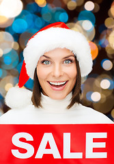 Image showing happy woman in santa hat with christmas sale sign