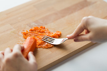 Image showing hand with fork making mashed carrot on board