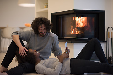 Image showing multiethnic couple using tablet computer on the floor