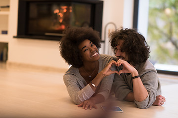 Image showing multiethnic couple showing a heart with their hands on the floor