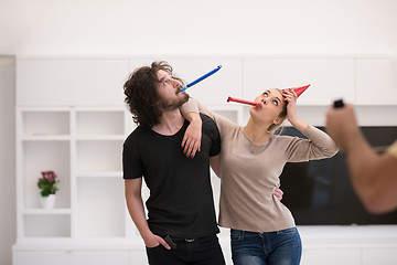 Image showing couple in party hats blowing in whistle