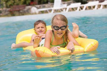 Image showing Two happy children playing on the swimming pool at the day time.