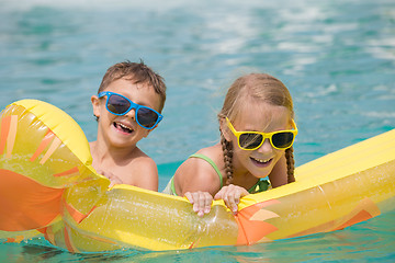 Image showing Two happy children playing on the swimming pool at the day time.