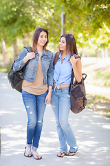 Image showing Two Beautiful Young Ethnic Twin Sisters With Backpacks Walking O