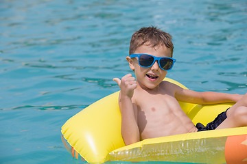 Image showing happy child playing on the swimming pool at the day time.