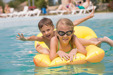 Image showing Two happy children playing on the swimming pool at the day time.