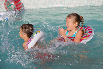 Image showing Two happy children playing on the swimming pool at the day time.