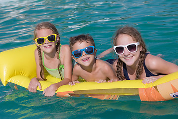 Image showing Three happy children playing on the swimming pool at the day tim
