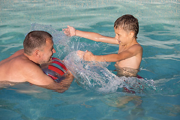 Image showing Father and son  playing in the swimming pool at the day time.