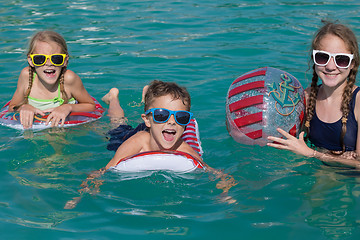 Image showing Three happy children playing on the swimming pool at the day tim