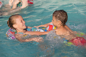 Image showing Two happy children playing on the swimming pool at the day time.