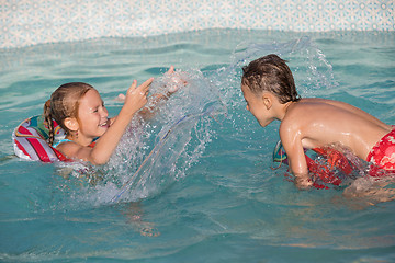 Image showing Two happy children playing on the swimming pool at the day time.