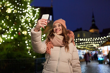 Image showing young woman taking selfie over christmas tree