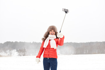 Image showing happy woman with selfie stick outdoors in winter