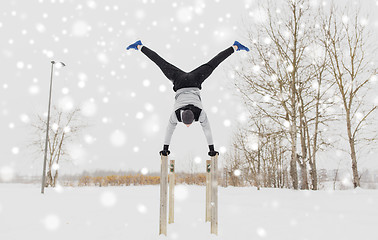 Image showing young man exercising on parallel bars in winter